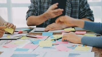 Two creative business people meeting and planning use post it notes sticky note on desk to share idea, Analysis data chart and graph with teamwork strategy brainstorming in office. video