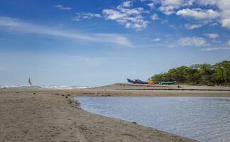 four boats parked on the sand, fishing boats parked near the ocean, boats stranded on the ocean shore with blue sky photo