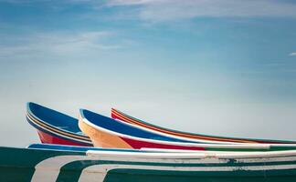 wooden boats parked on the sand, colorful fishing boats parked near the ocean, closeup of boats stranded on the ocean shore with blue sky and copy space photo