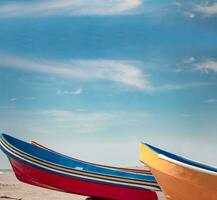 wooden boats parked on the sand, colorful fishing boats parked near the ocean, closeup of boats stranded on the ocean shore with blue sky and copy space photo