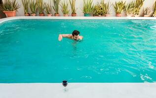 Handsome man on vacation swimming in a hotel pool, Man on vacation swimming in a blue swimming pool. Young man swimming in a tropical hotel pool photo