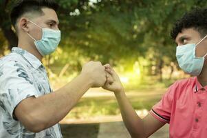 Two young men clashing their fists, image of two young men bumping their fists in a friendly way, close up of two fists bumping in a friendly way photo