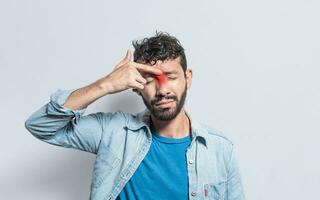 Young man with pain touching nose. A person with nasal bridge pain, Man with nasal bridge headache. Sinus pain concept photo