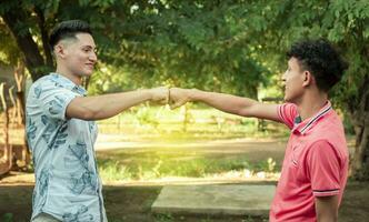 Two young men clashing their fists, image of two young men bumping their fists in a friendly way, close up of two fists bumping in a friendly way photo