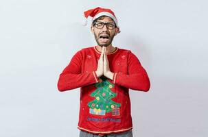 Man with christmas hat with hands together in pleading gesture. Christmas guy with hands together begging for a Christmas wish, Person in christmas hat with desperate pleading gesture photo