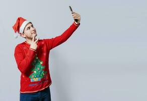 Happy handsome man in christmas hat taking a selfie. Happy guy taking a christmas selfie on isolated background, Smiling young man in christmas hat taking a selfie isolated photo