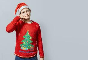 hombre en Navidad ropa imitando un teléfono conversación, joven latín hombre en Navidad sombrero haciendo un llamada gesto aislado. personas en Navidad ropa haciendo un llamada gesto con su dedos foto