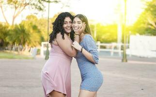 Two female friends hugging in front outdoors, girl friends hugging and enjoying life, women friendship concept photo