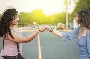 Two girls shaking fist, Two woman clashing their fists, image of two girl bumping their fists in a friendly way photo