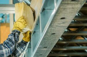 Construction Worker Insulating Frame Elements with a Mineral Wool photo