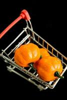 Grocery cart with decorative pumpkins on a black background. The concept of the autumn sales. Black Friday and cyber Monday. selective focus photo