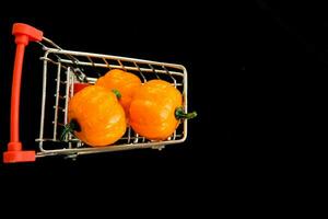 Grocery cart with decorative pumpkins on a black background. The concept of the autumn sales. Black Friday and cyber Monday. selective focus photo