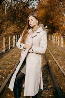 beautiful long-haired woman walks through the autumn streets. Railway, autumn, woman in a coat. photo