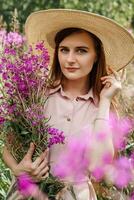 young girl in nature with a bouquet of pink wild flowers. A bouquet of Ivan-tea in the hands of a woman. photo