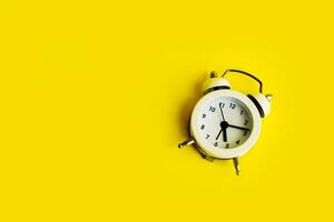 White alarm clock on a yellow background. Empty space for text. photo