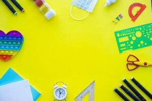 Close up of stationery and silicone toy popit. Flat lay composition. Yellow background. Space for text. Back to school photo