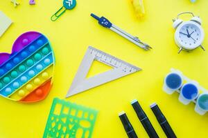 Close up of stationery and silicone toy popit. Flat lay composition. Yellow background. Space for text. Back to school photo