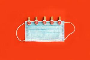 Christmas decorations decorative background. Decorative pins in the form of red gloves on the medical masks. Top view, minimalism, flat layout. Christmas and New year 2020. The Age Of Coronavirus. photo
