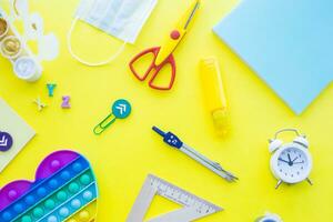 Close up of stationery and silicone toy popit. Flat lay composition. Yellow background. Space for text. Back to school photo