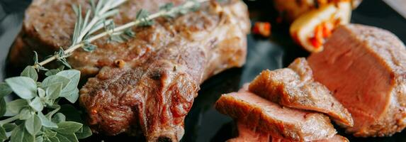 Beef steaks on a black plate with greens. photo