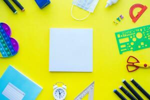 Close up of stationery and silicone toy popit. Flat lay composition. Yellow background. Space for text. Back to school photo