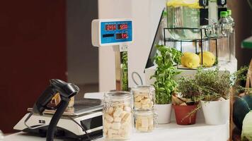 Close up of electronic scale in eco friendly zero waste supermarket next to organic produce. Panning shot of weighing machine in local neighborhood shop used for bulk products video