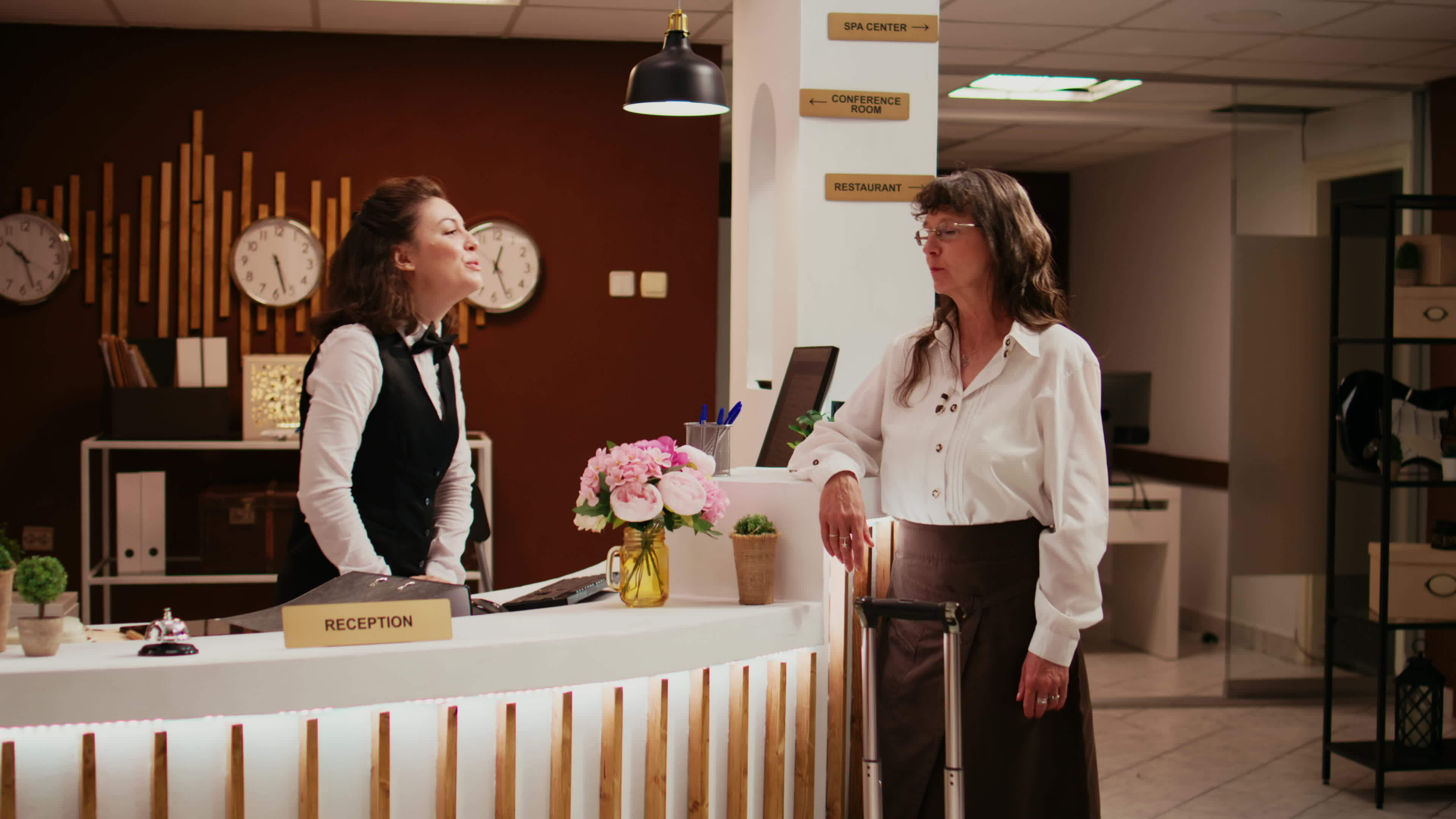 Diverse team greeting tourist at hotel, helping with check in process ...