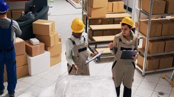 Depot workers planning shipment and distribution in warehouse space, analyzing list of stock inventory. Storage room manager organizing industrial goods in cardboard boxes, small business. photo