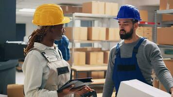 Multiethnic team of workers scanning merchandise barcodes, looking at products packed in cardboard boxes. Male employee bringing goods in package to supervisor, planning shipment. photo