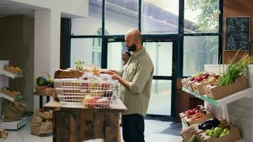 uomo a zero rifiuto eco supermercato ricerca per salutare cibo alternative e dispensa forniture, godendo shopping a Locale biologico drogheria negozio. cliente nel eco amichevole negozio supporto piccolo attività commerciale. video