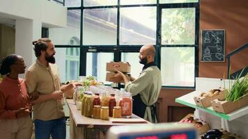 Pareja secundario local comerciante por comprando eco recién cosechado frutas y verduras, mirando para natural artículos en cero residuos supermercado. pequeño negocio propietario saludo los compradores con muestras video