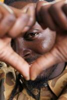 Excited man doing heart shape symbol in front of camera, smiling during valentine s day studio shot. African american person making love sign with fingers over yellow background. Positive concept photo