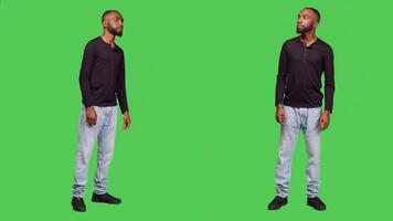 Relaxed friendly person smiling in front of camera, feeling positive and confident over full body green screen background. Young man being cheerful and optimistic standing in studio. photo