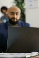 árabe empresa empresario asistiendo vídeo llamada inversor utilizando ordenador portátil en ocupado oficina. ejecutivo gerente discutir proyecto estrategia compañeros de trabajo virtual reunión en trabajo colaborativo espacio foto