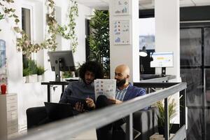 Arab entrepreneurs reviewing business strategies and analyzing papers with statistics charts. Company employees checking analytics report in corporate coworking space office photo