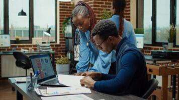 Employees working on data reports plans for business development, using annual statistics on papers to increase profit. Office workers checking analytics on laptop, coworking space. photo