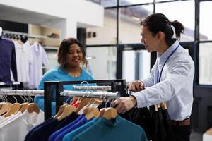 africano americano cliente mirando a casual tener puesto, compras para elegante mercancías en moderno boutique. adicto a las compras mujer falto nuevo armario, comprando de moda ropa en ropa Tienda foto