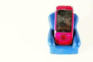 a broken phone sitting on top of a blue chair photo
