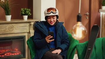 Guest texting messages on phone, asking friends to meet skiing on slopes at mountain complex. Winter sport enthusiast checking smartphone app and social media before leisure activity. video