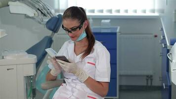 Female dentist uses cellphone at the dental clinic video