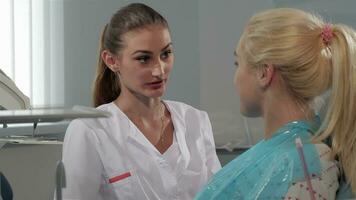 Dental surgeon talks with her patient at the dentist cabinet video