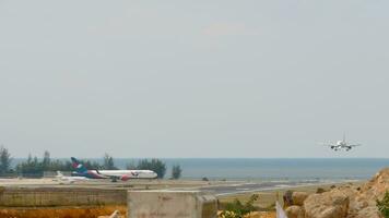 PHUKET, THAILAND JANUARY 29, 2023 Aircraft landing at Phuket airport. Airfield against the backdrop of the sea. Jet of Azur Air waiting in line for departure video