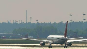 MOSCOW, RUSSIAN FEDERATION JULY 30, 2021 Airplane speeding up for takeoff, rear view. Jet plane backlit on the runway. Row of airplanes parked video