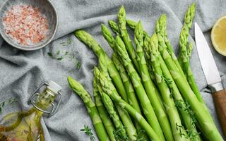 Bunch of raw asparagus stems with different spices photo