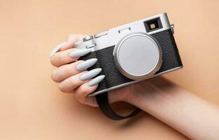 Woman's hand with grey nail polish holding camera photo