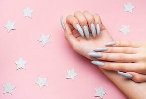 Hands with grey manicure on a pink background photo