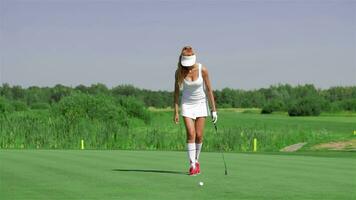 Woman stands on her knee at the golf video
