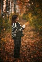 girl with freckles with a book among autumn leaves photo