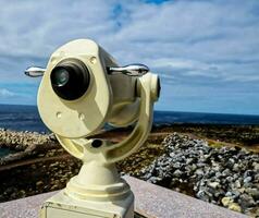 un moneda operado telescopio en un rock repisa con vista a el Oceano foto