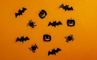 Halloween background, paper black bats, pumpkins and spiders on orange background. photo